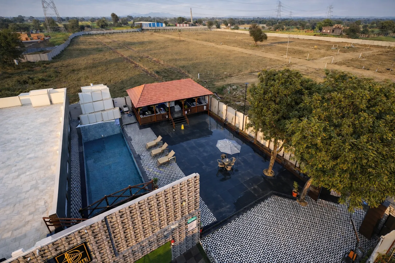 Aerial drone view of Definite Infra plotted township near Alwar, Rajasthan showing developed internal roads, open residential plots, green areas, and on-site amenities