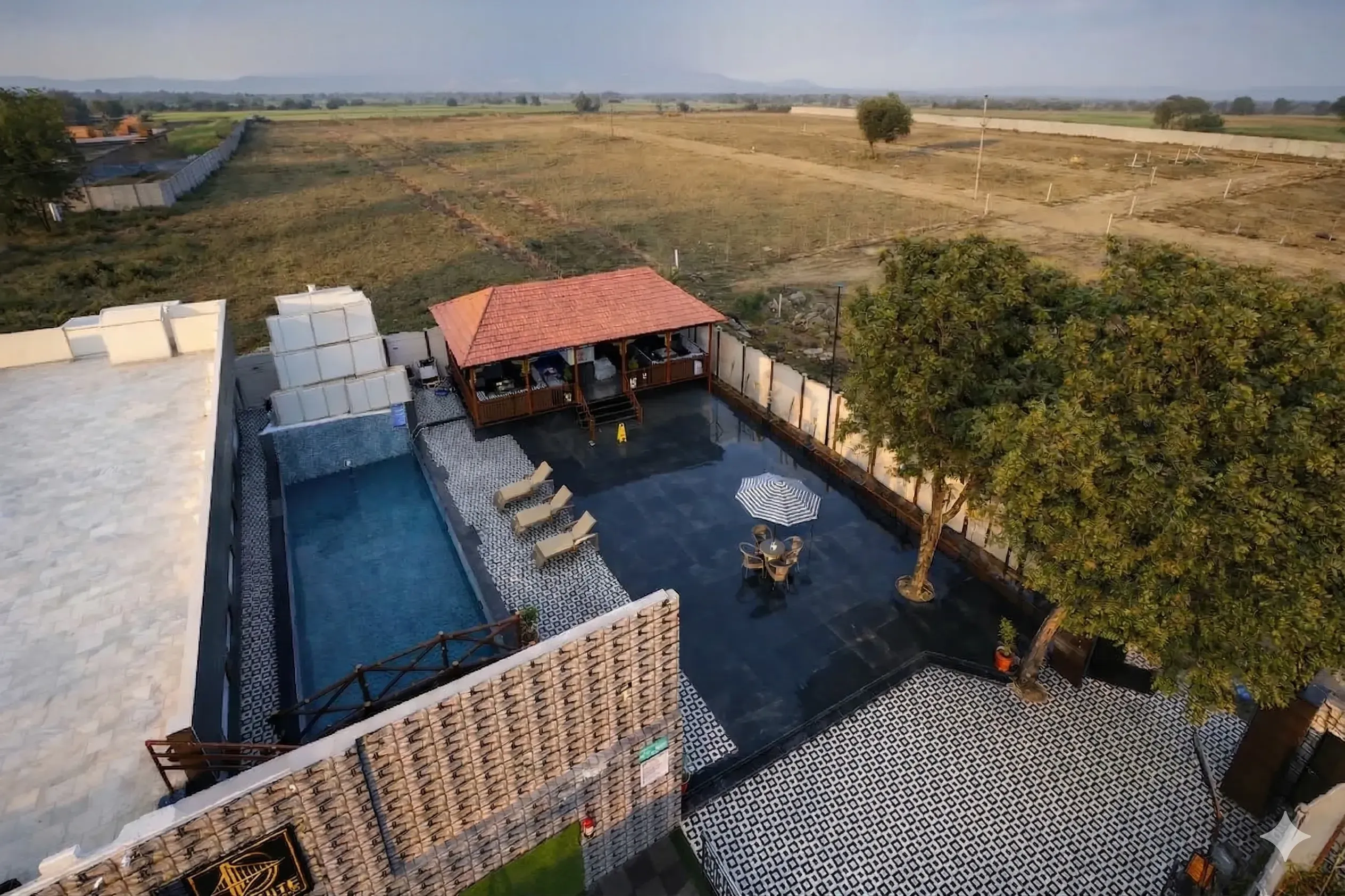 Aerial drone view of Definite Infra plotted township near Alwar, Rajasthan showing developed internal roads, open residential plots, green areas, and on-site amenities